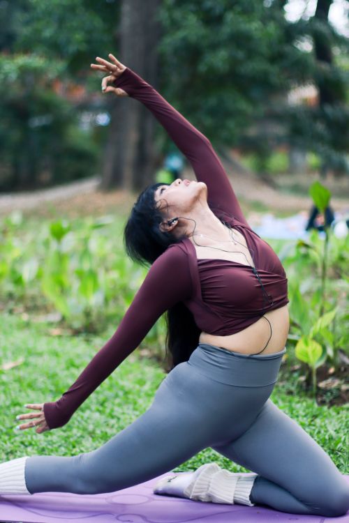 Free Woman practicing yoga in a lush Jakarta park, showcasing grace and flexibility. Stock Photo