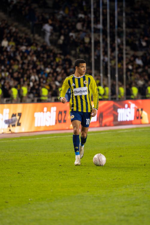Free A soccer player in a blue and yellow uniform dribbles during a night match in Baku, Azerbaijan. Stock Photo