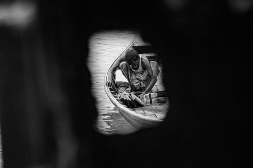 Free Black and white photo of a man in a boat seen through a creative framing. Stock Photo