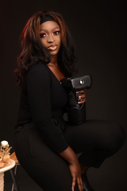 Free Elegant portrait of a female photographer in black attire, showcasing confidence and style. Stock Photo