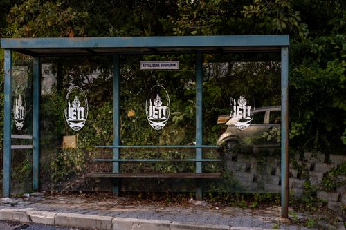 Free A vacant bus stop named Ayvalidere Sondurak amidst urban foliage with a car parked nearby. Stock Photo