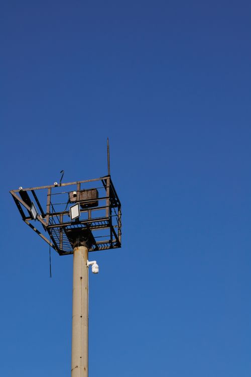 Free A solitary industrial watchtower set against a crisp blue sky, evokes openness and vigilance. Stock Photo