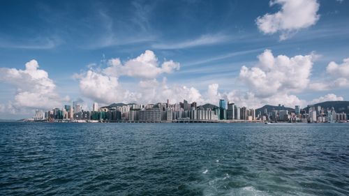 Free Picturesque scenery of Victoria Harbor with various modern skyscrapers situated on shore of rippling river against cloudy blue sky in Hong Kong Stock Photo