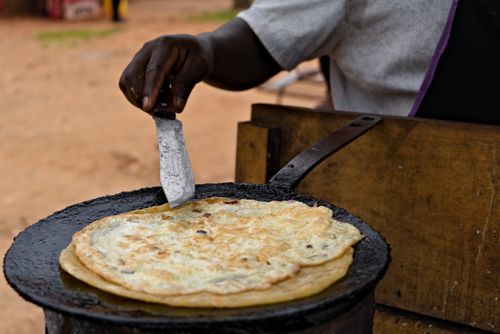 Free A close-up of a street vendor preparing a traditional Ugandan dish, showcasing cultural cuisine. Stock Photo