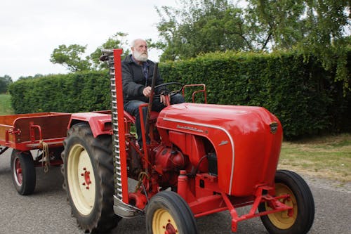 Man in Black Jacket Riding Red Tractor
