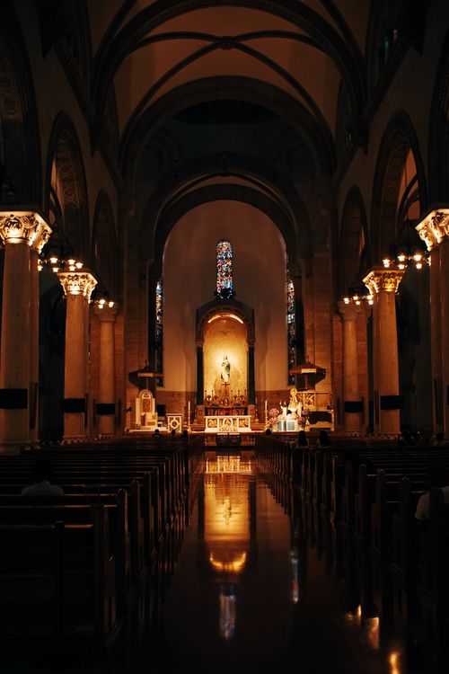 Free Warmly lit church interior showcasing majestic architecture and stained glass. Stock Photo
