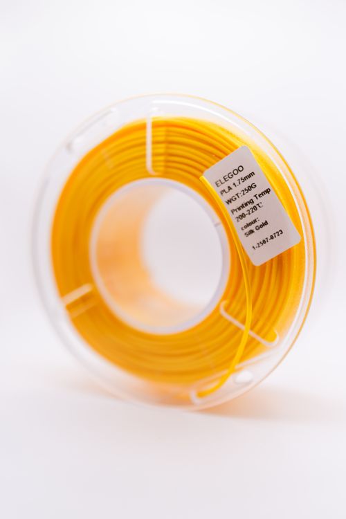 Free A close-up of a yellow PLA filament spool used for 3D printing with specific printing temperatures. Stock Photo