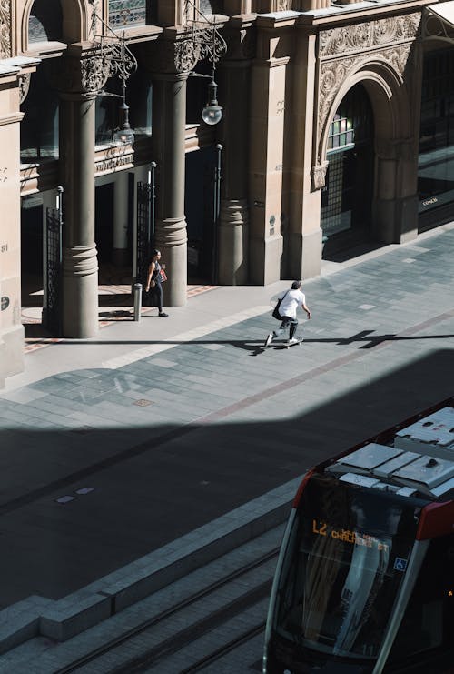 Man in White Shirt and Black Pants Skateboarding on Sidewalk