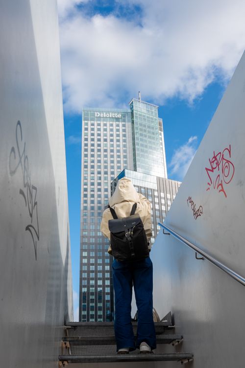 Free A person ascends a stairway with a view of a modern skyscraper under a blue sky in Rotterdam. Stock Photo