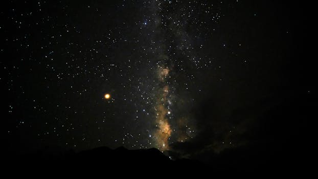 A breathtaking view of the Milky Way galaxy and a star-filled night sky over silhouetted mountains.