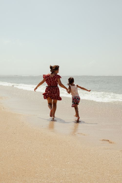 Free A joyful moment of a mother and child walking on a sunny beach in Bali, Indonesia. Stock Photo