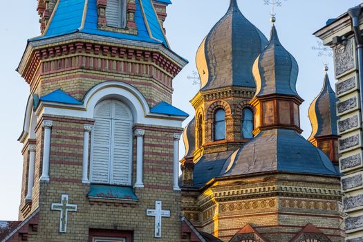 Close-up of an Eastern Orthodox church with detailed decorative brickwork and blue domes in daylight.