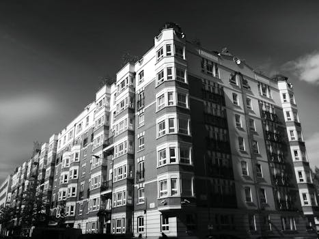 Black and white photo of a classic urban apartment building facade with windows.