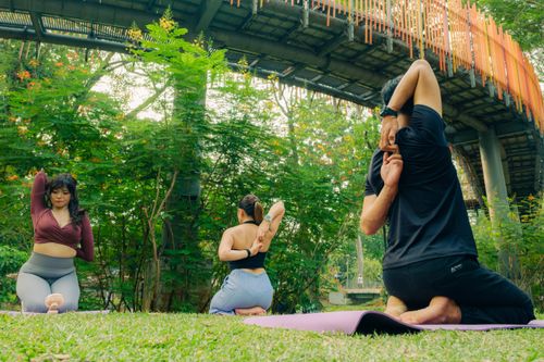 Free Diverse group practicing yoga in a serene park setting under an urban bridge. Stock Photo