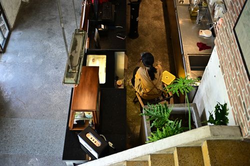 Free Aerial perspective of a coffee shop with a barista preparing drinks, capturing an industrial aesthetic. Stock Photo