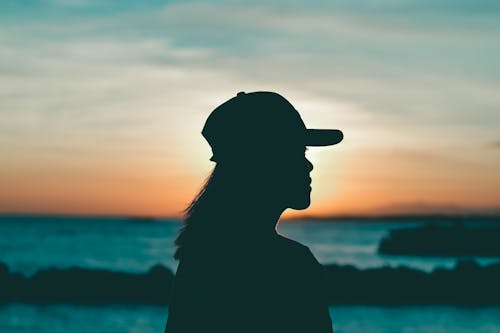 A Silhouette of a Woman Wearing a Cap during the Golden Hour
