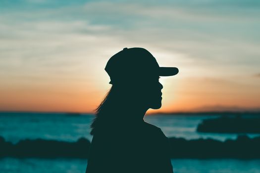 日落时分，一位戴帽子的女人在海面上映出迷人的轮廓