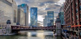 在芝加哥沿河的天际线下，多云的天空中耸立着标志性的桥梁和摩天大楼，景色令人惊叹