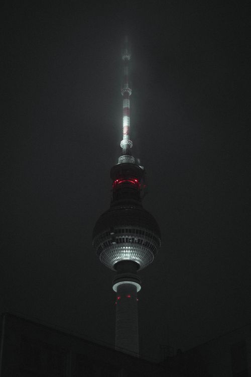 Free Atmospheric night view of Berlin's iconic TV Tower (Fernsehturm) glowing through the mist. Stock Photo