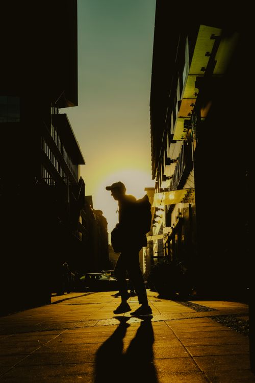 Free Dramatic silhouette of a person walking in Warsaw, Poland, against a vibrant sunset sky. Stock Photo