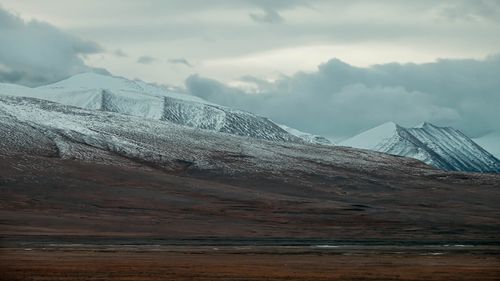 Free Stunning view of snow-covered mountains with a dramatic cloudy sky. Stock Photo