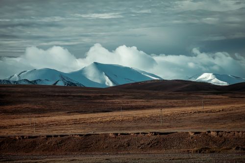 Free Panoramic view of snow-capped mountains under a dramatic sky, ideal for nature and travel themes. Stock Photo