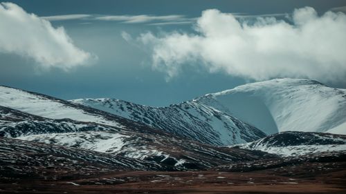 Free Scenic view of a mountain range with snow-capped peaks under a dramatic sky with clouds. Stock Photo