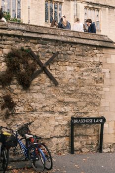 Bicycles parked along Brasenose Lane against an old stone wall in Oxford, England.