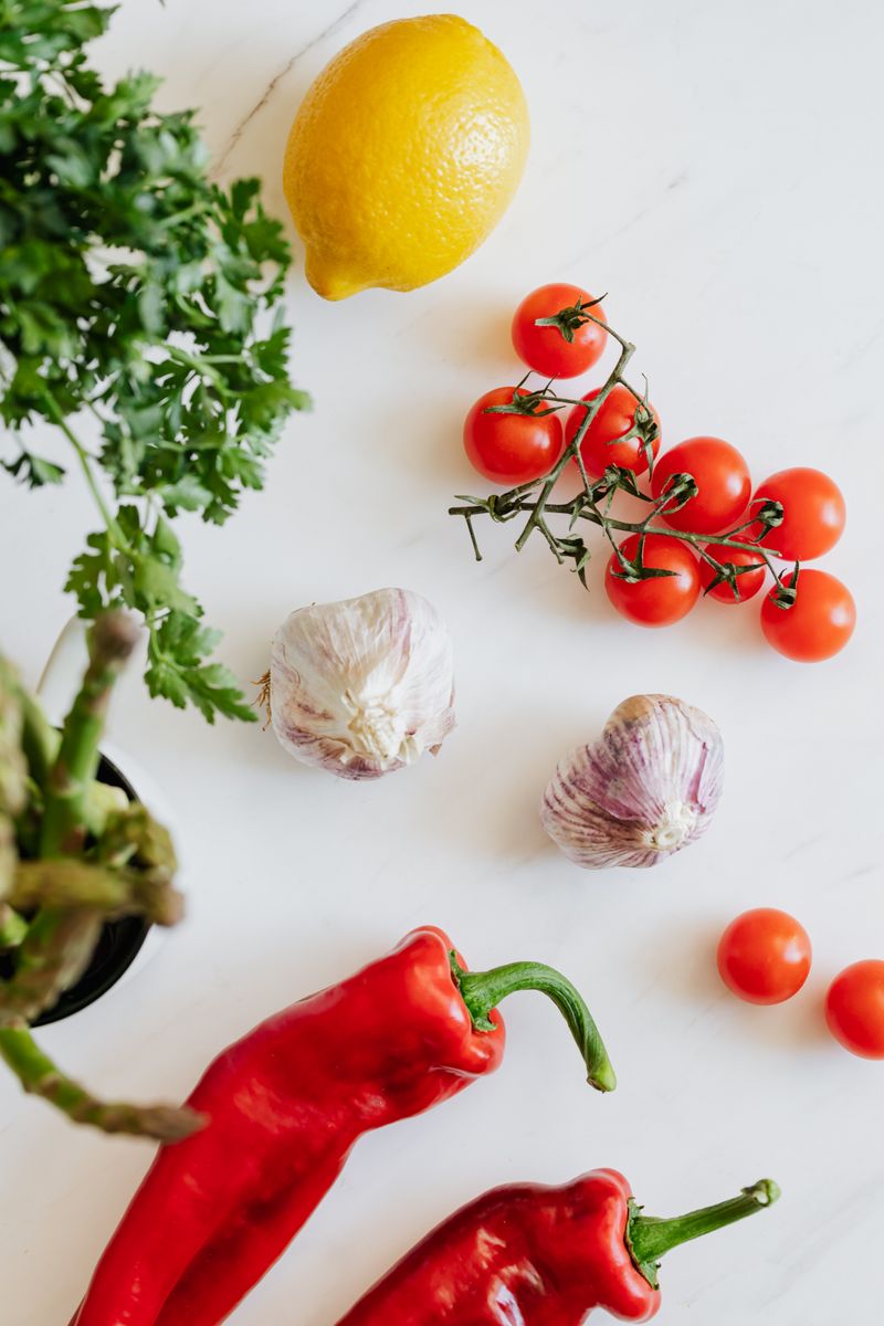 Top view of various fresh ripe vegetables and lemon placed on white smooth surface