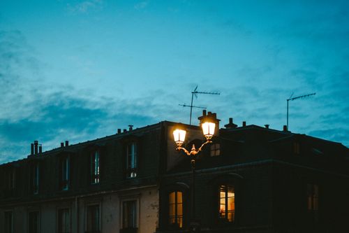 Free A picturesque urban rooftop with a vintage lamp post glowing at twilight under a serene sky. Stock Photo