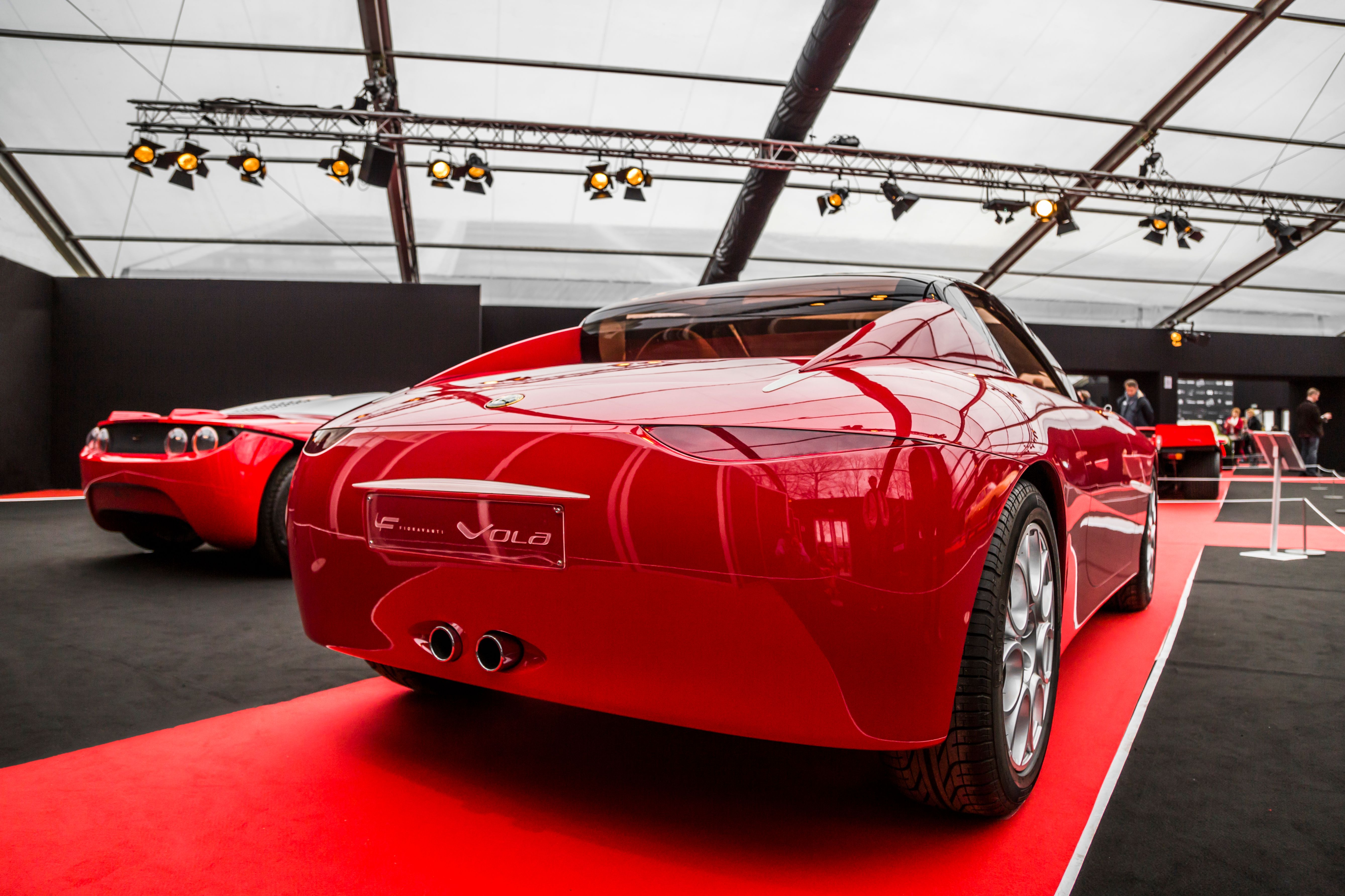 Red sports car displayed at an indoor auto show.