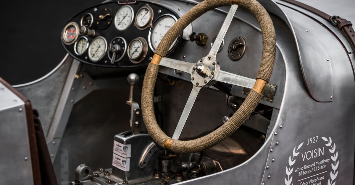 Close-up of the dashboard and steering wheel of a classic Voisin race car, showcasing detailed instrumentation.