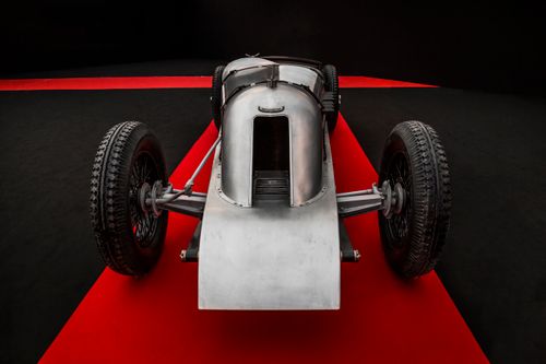 Free Classic vintage racing car showcased on a red carpeted floor, elegant and historic. Stock Photo