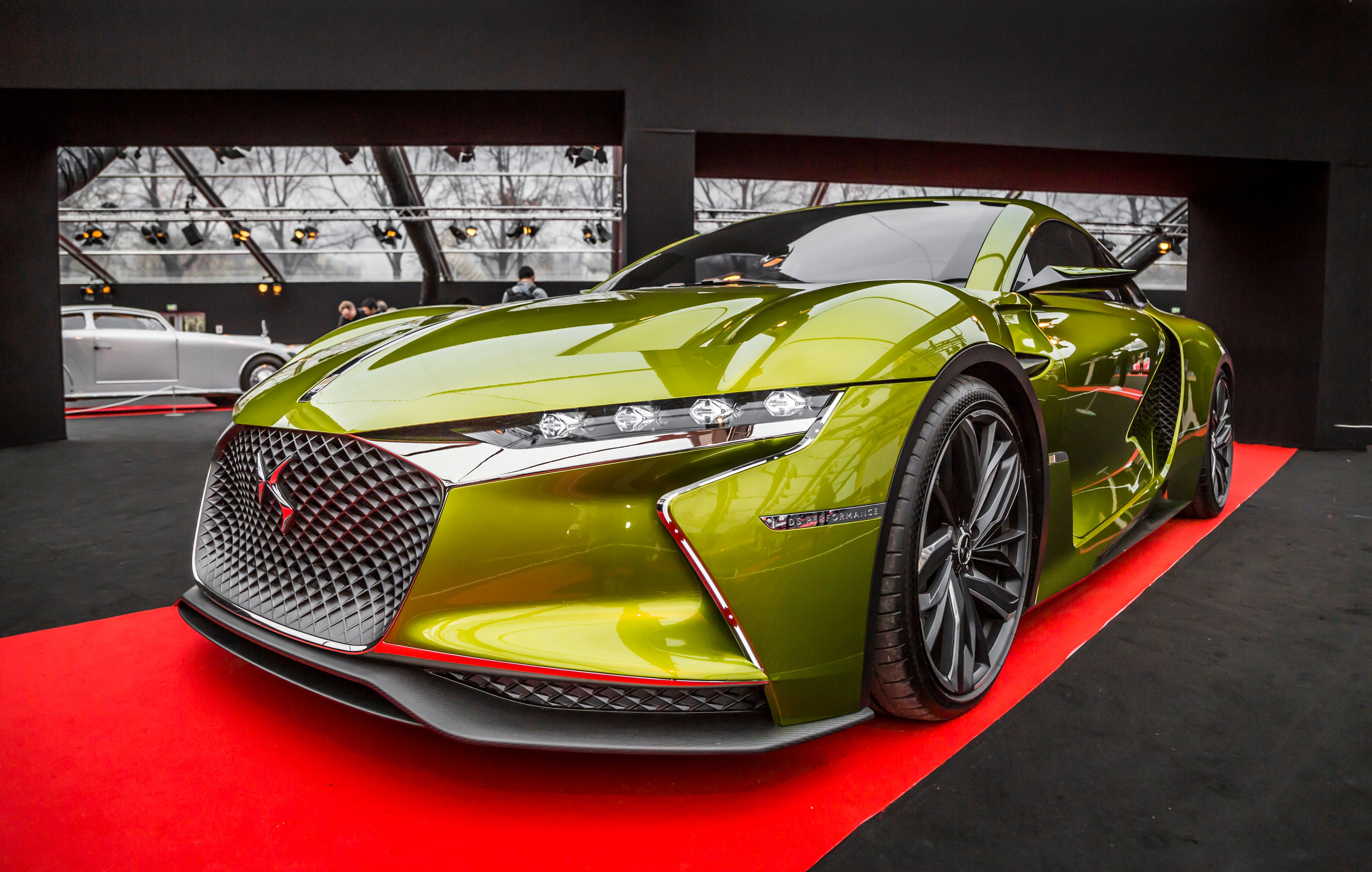 Green sports car showcased on a red carpet under showroom lighting