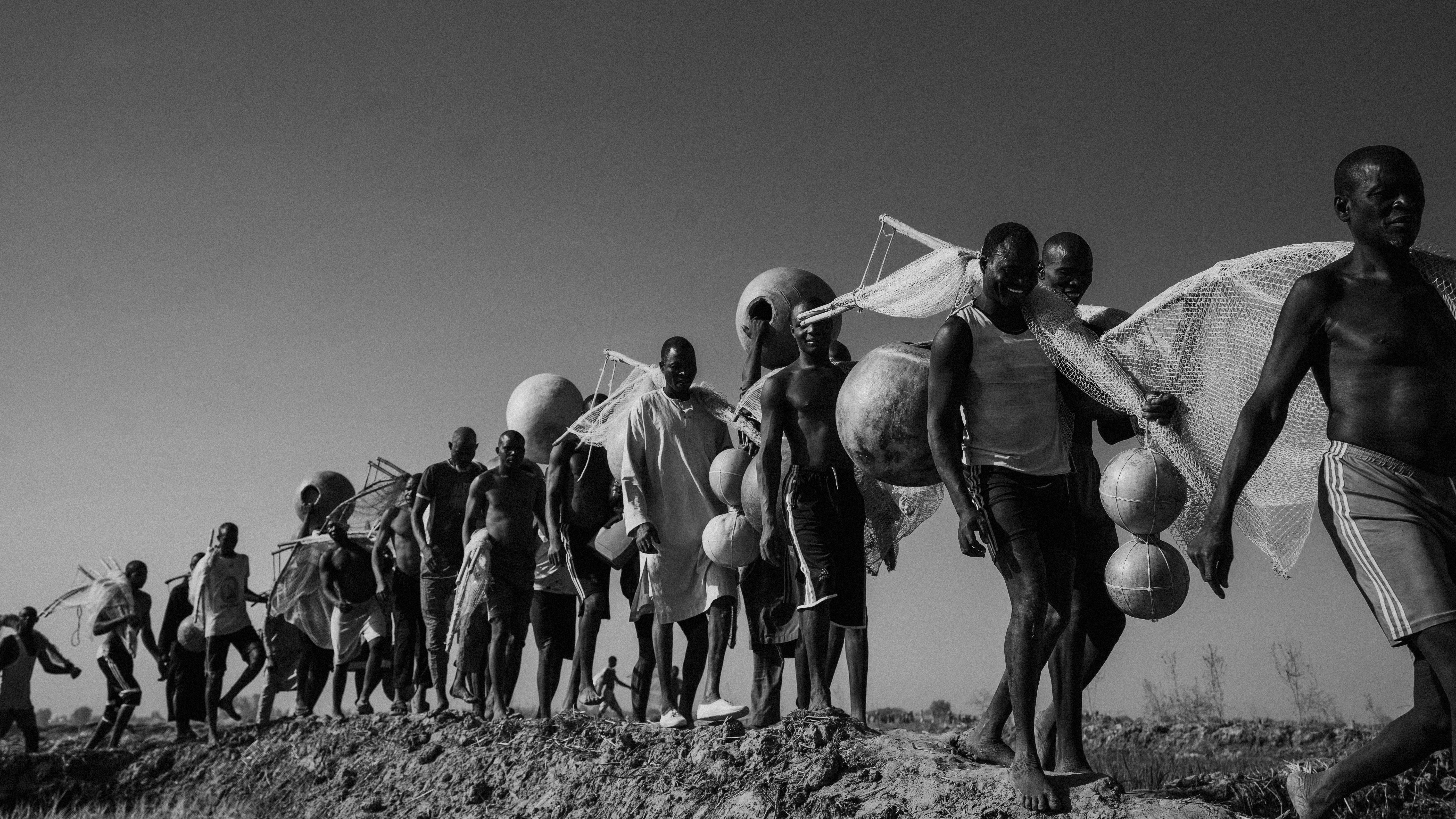 A group of men in Nigeria walk with fishing gear, showcasing traditional fishing culture.