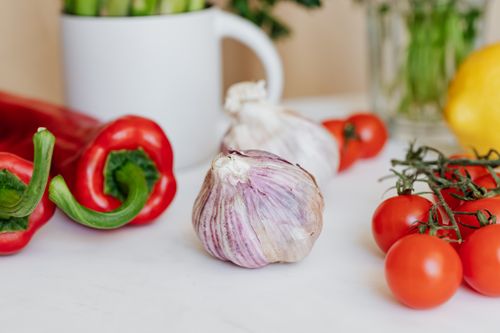 Free Close-up of fresh tomatoes, garlic, and red peppers on a white table, ideal for culinary projects. Stock Photo