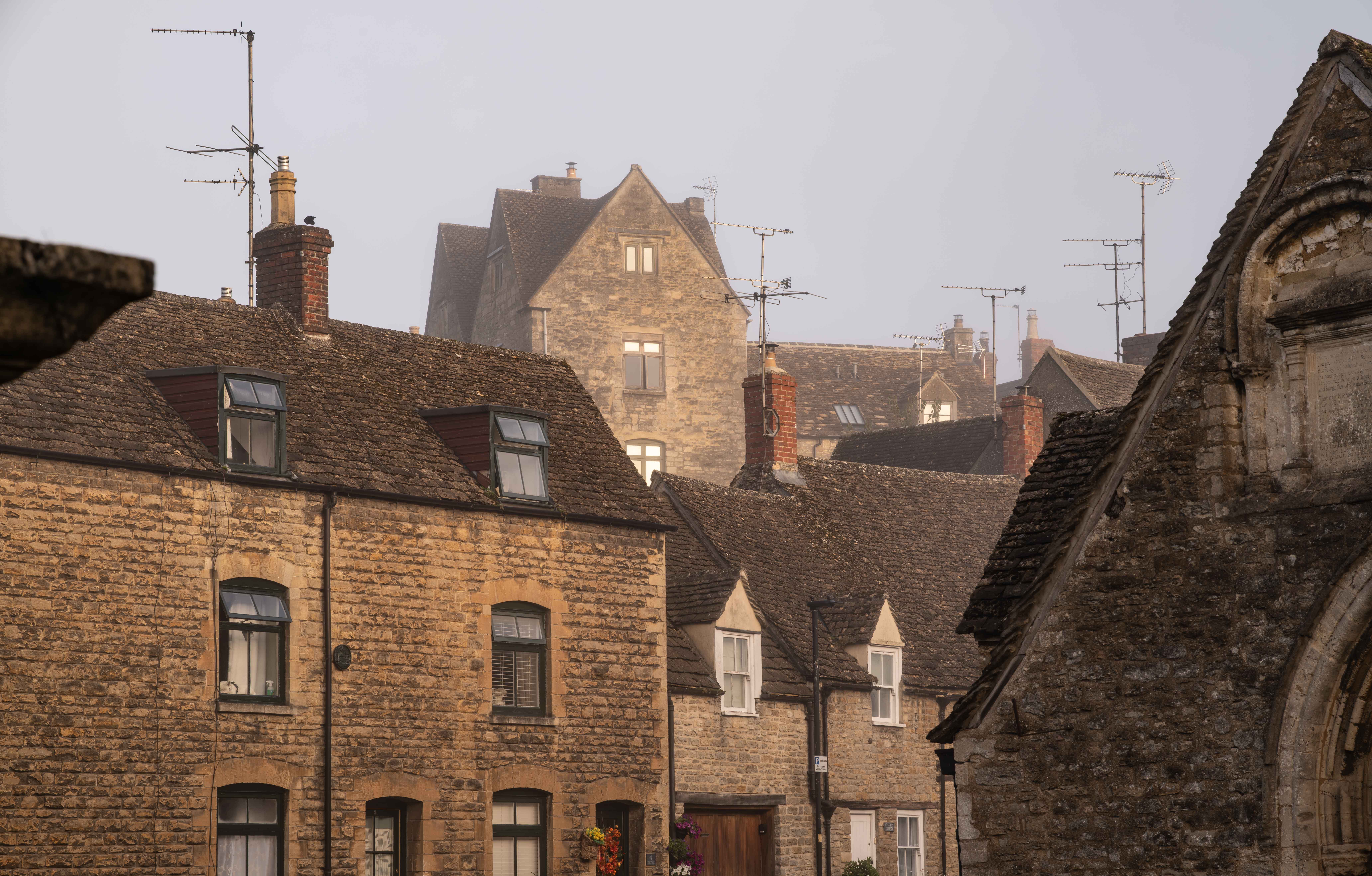 Charming stone buildings under a misty sky in a quaint village setting.