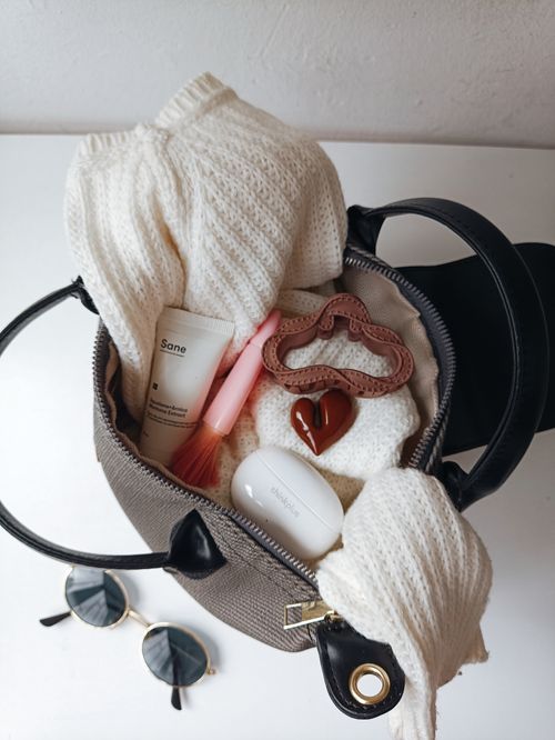 Free Chic handbag filled with sweater, sunglasses, and beauty essentials. Stock Photo