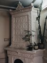 Green potted plants placed on vintage white stucco fireplace with ornamental carving in room