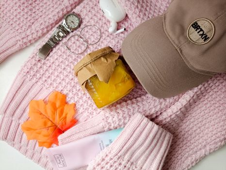 Stylish autumn ensemble with a knitted sweater, cap, watch, and homemade jam.