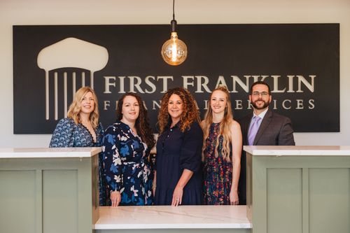 Free Five professionals standing in an office lobby with company signage in background. Stock Photo