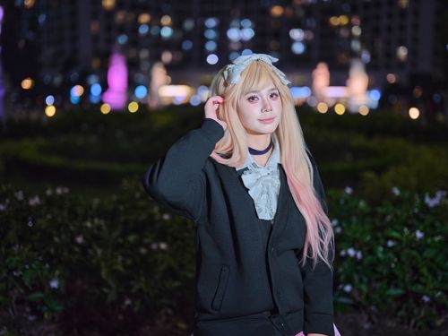 Free A cosplayer in a cute outfit poses outdoors at night with city lights in the background. Stock Photo