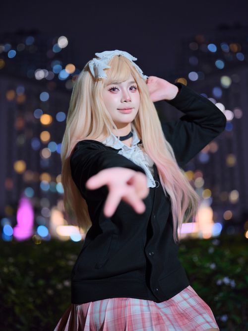 Free A cosplayer poses in an urban night setting with vibrant city lights. Stock Photo
