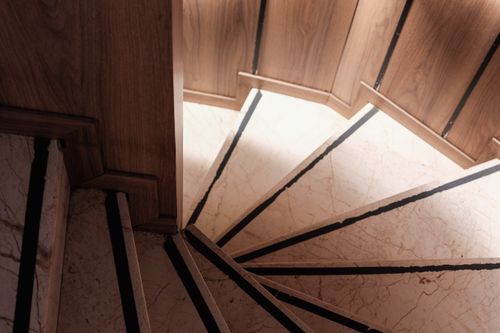 Free A captivating view of spiral marble stairs framed by wooden paneling in soft light. Stock Photo