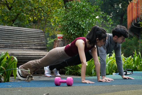 Free A man and woman perform push-ups in a scenic outdoor park, promoting fitness and healthy lifestyle. Stock Photo