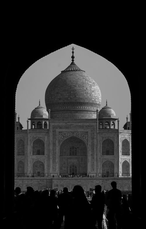 Free Black and white photo of the Taj Mahal framed through an archway, showcasing its architectural beauty. Stock Photo