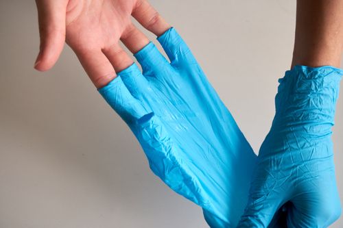 Free Close-up of hands putting on disposable blue latex gloves for safety and hygiene. Stock Photo