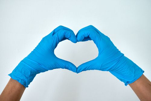 Free Hands wearing blue gloves forming a heart shape, symbolizing healthcare support and love. Stock Photo