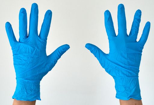 A pair of hands wearing blue latex gloves for hygienic protection and safety.