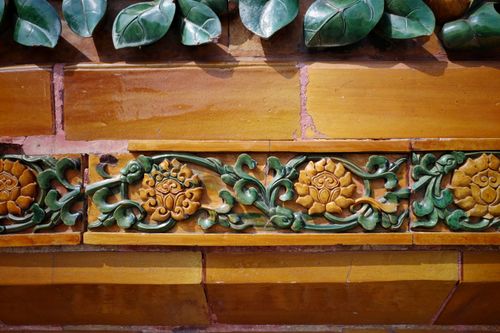 Free Intricate floral lotus carvings in green and gold on an architectural wall, showcasing craftsmanship. Stock Photo